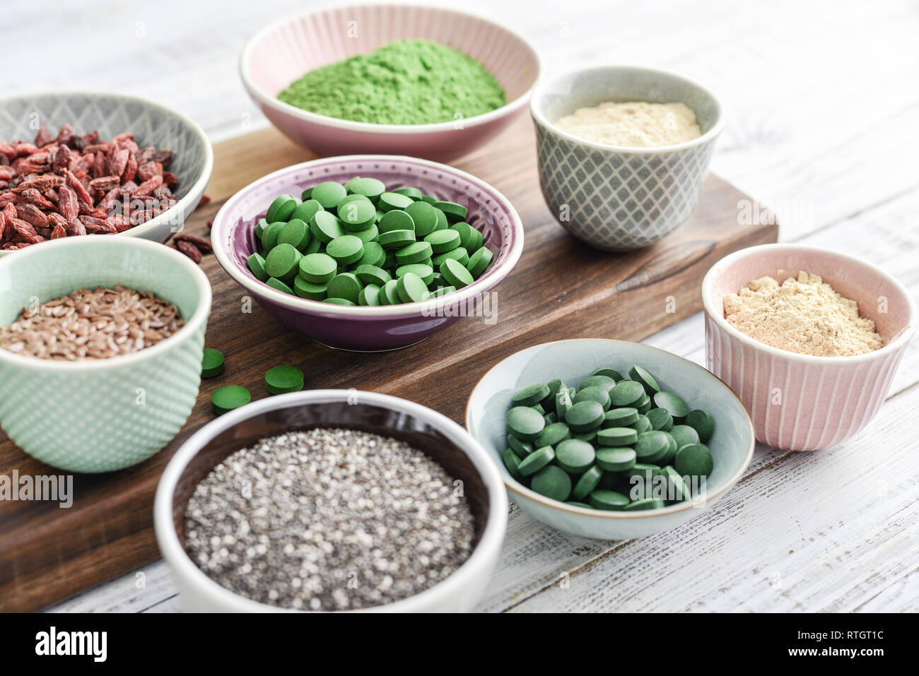 Different super foods in bowls on white wooden background closeup Stock