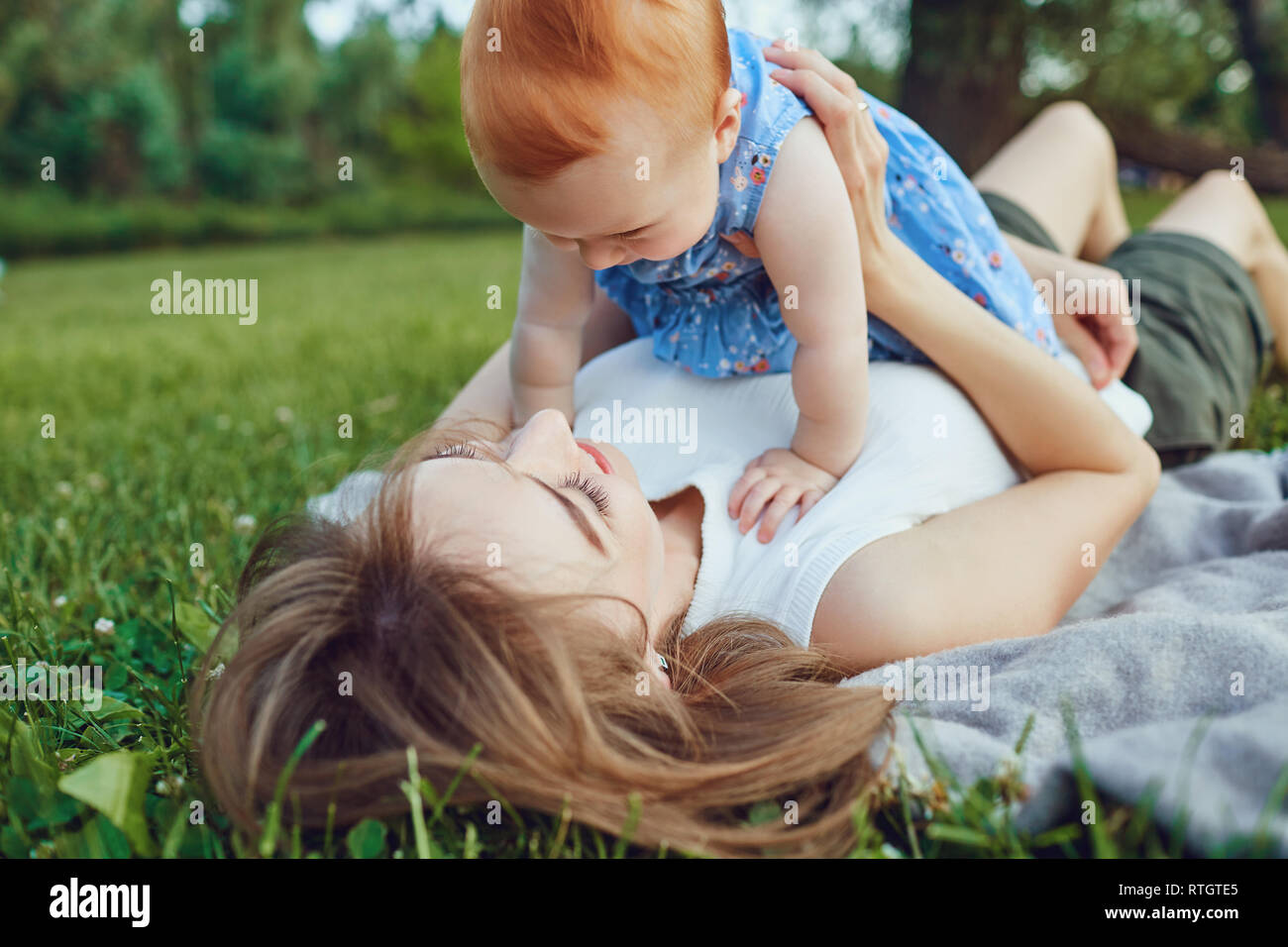 Woman with child lying on green meadow Stock Photo