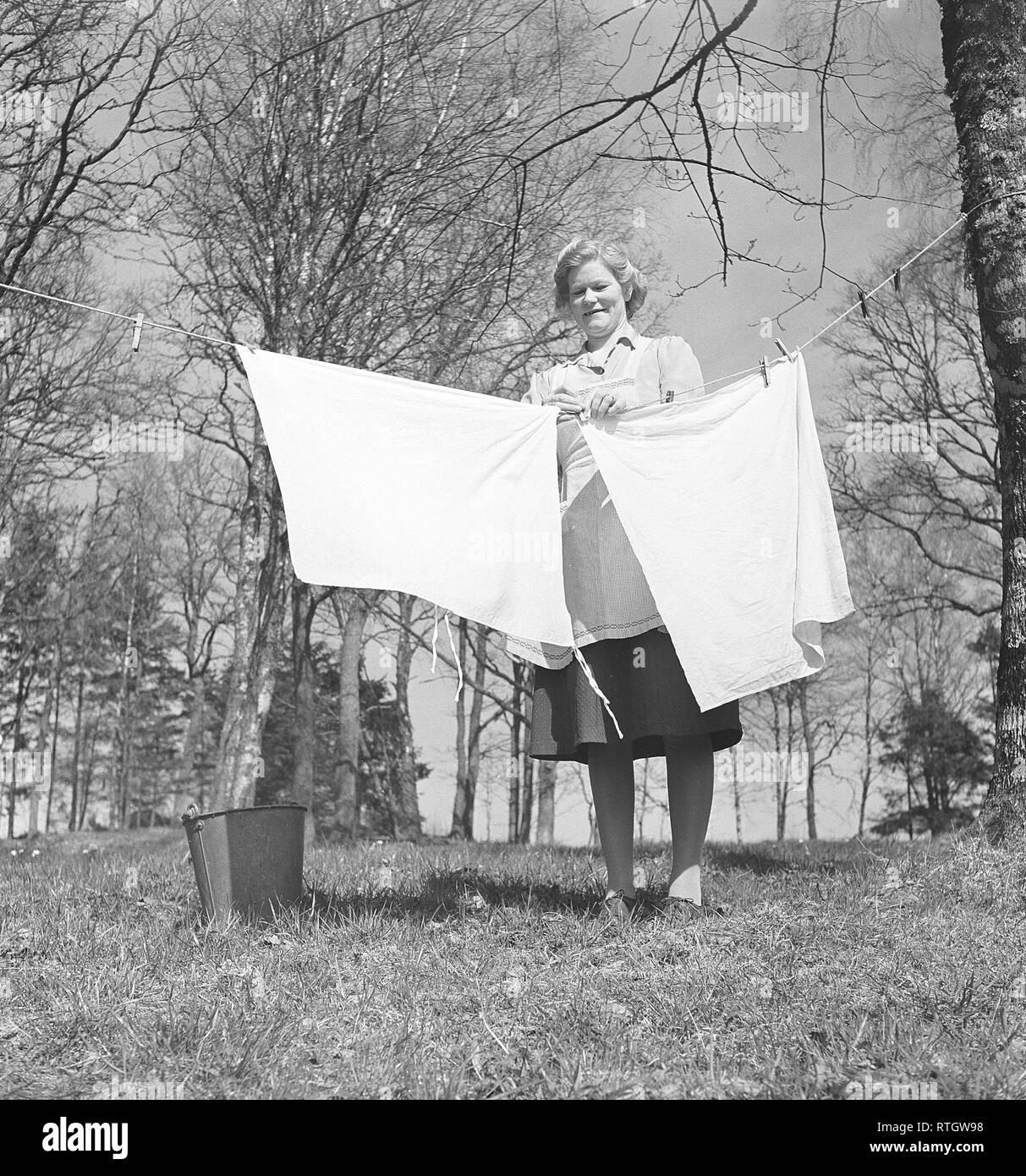 Doing the laundry in the 1950s. A lady is out in the garden hanging up the laundry to dry. Photo Kristoffersson ref BC7-8. Sweden 1951 Stock Photo