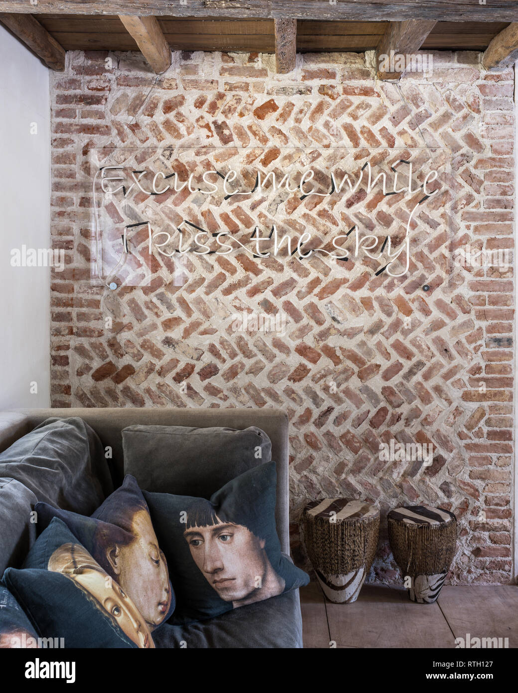Medieval herringbone brickwork with portrait cushions printed for Mirka McNeill by Digitex with neon quote from Jimmy Hendrix Stock Photo