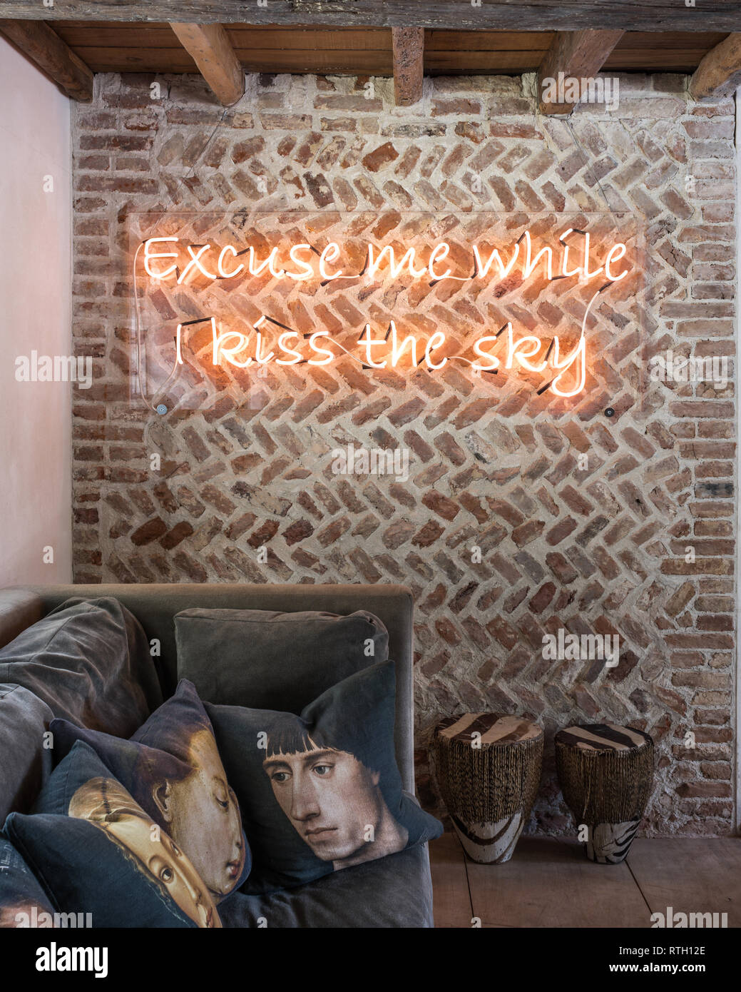 Medieval herringbone brickwork with portrait cushions printed for Mirka McNeill by Digitex with neon quote from Jimmy Hendrix Stock Photo
