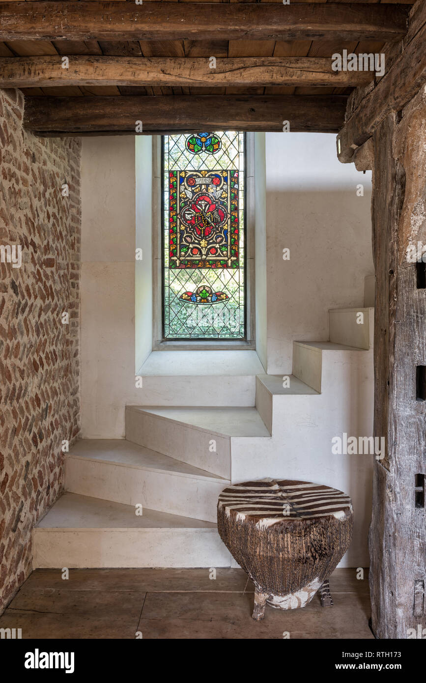 Helical stircase of Spanish limestone designed by Mirka McNeill with fragments of medieval glass set in tall leaded window Stock Photo