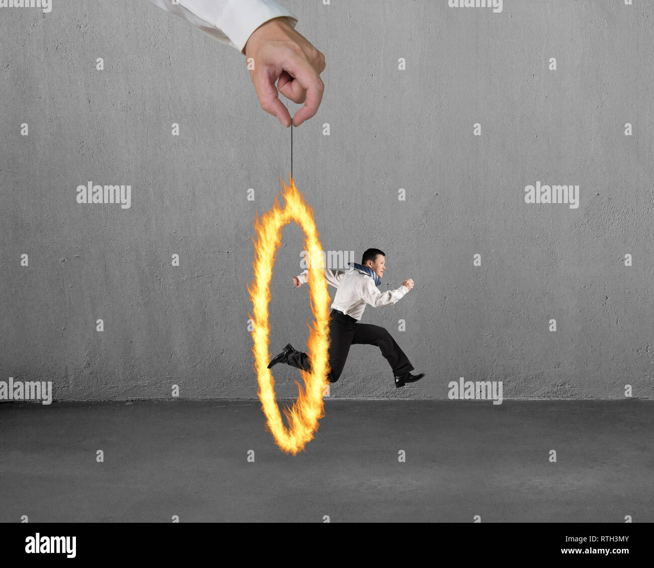 Man jumping through fire circle hand holding with concrete wall background Stock Photo Alamy