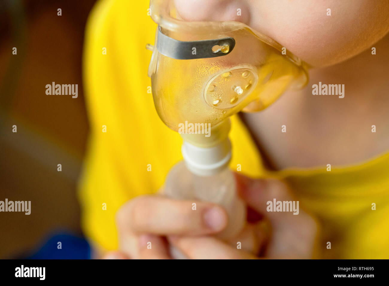 Child makes inhalation at home with nebulizer on out of focus background. Example of combating respiratory diseases such as tracheitis bronchitis pneu Stock Photo