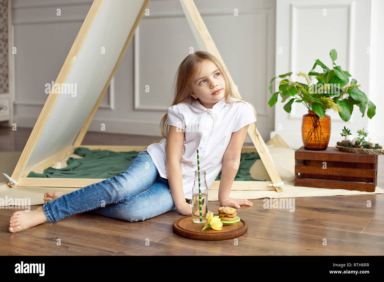 Cute Happy Little Girl With Blond Hair In A White Shirt And Blue