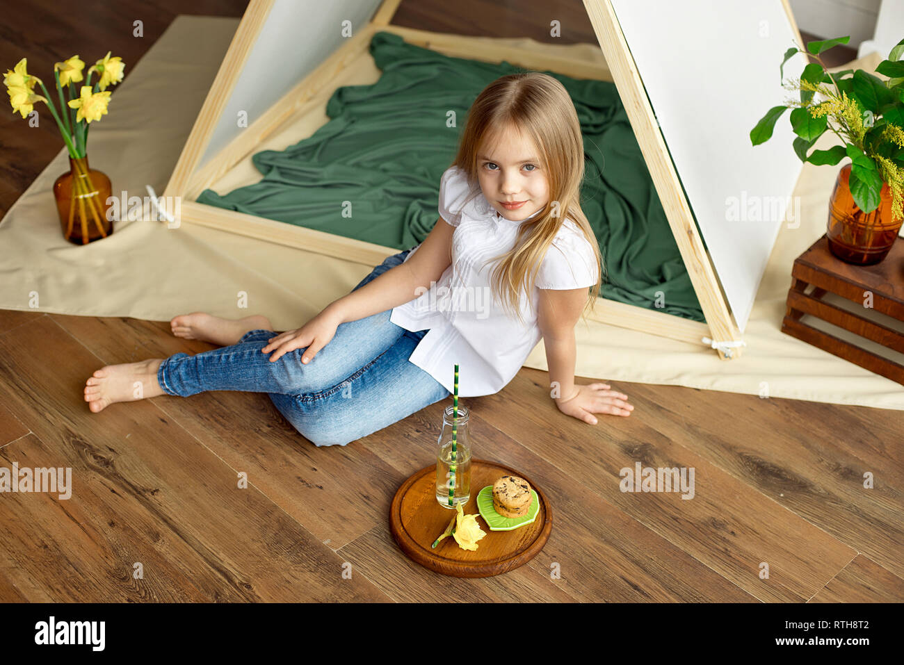 Cute Happy Little Girl With Blond Hair In A White Shirt And Blue