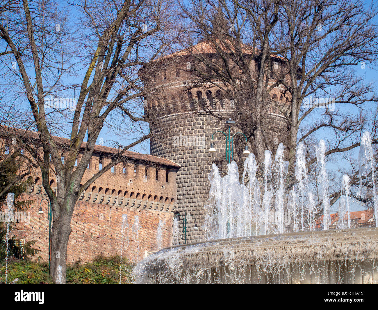 Tower of the Sforza Castle (Castello Sforzesco) through the jets of the fountain. Milan, Italy Stock Photo