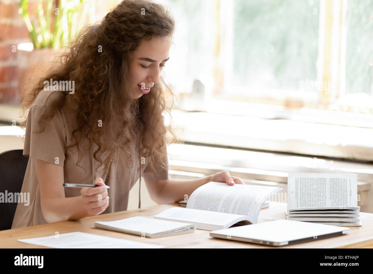 Teen girl college student studying reading textbooks learning making notes Stock Photo
