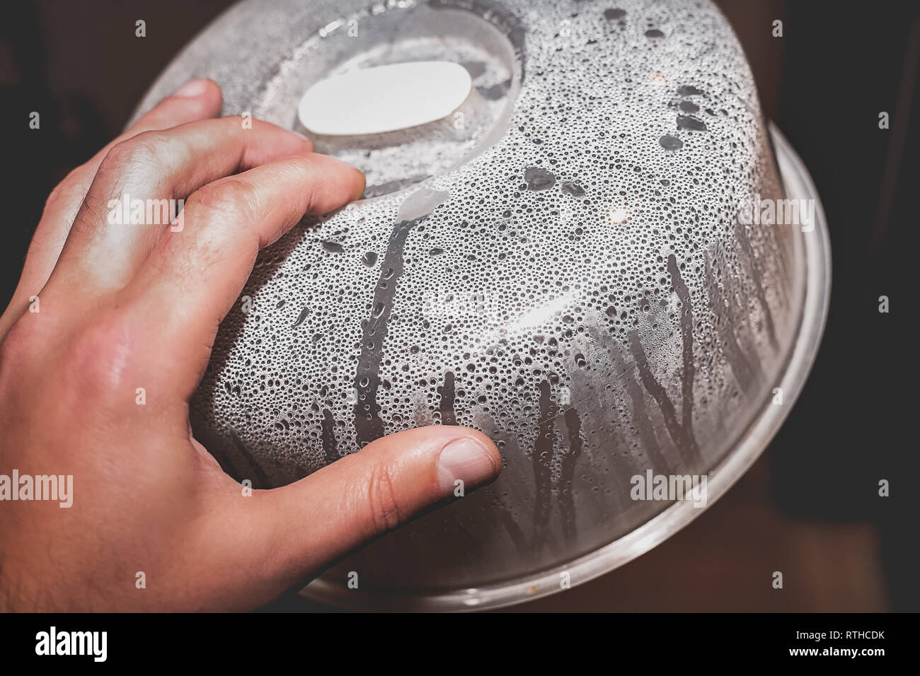 Hand with steamed cover for microwave closeup. Condensation and water  droplets on the surface of the plastic after heating food Stock Photo -  Alamy