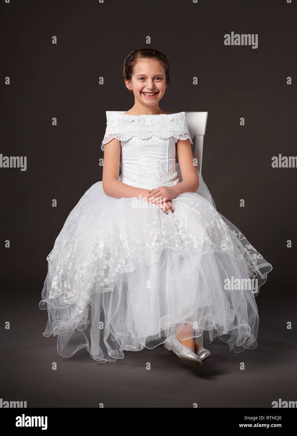 little girl dressed in a white ball gown and sitting on the chair, dark