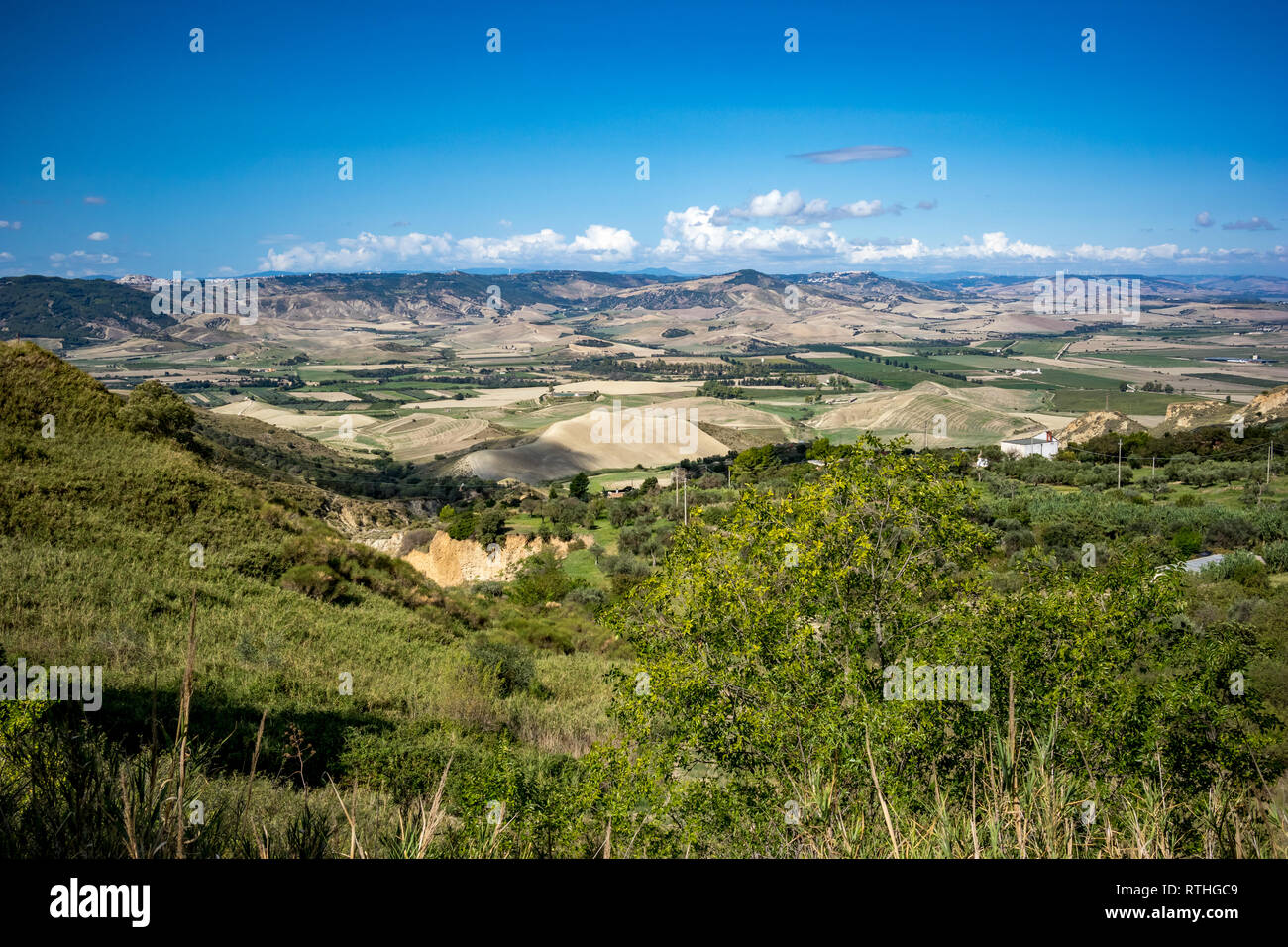 Valley countryside landscape, Basilicata, Italy, sunny summer day, green hills and clear blue sky, blurred wind power turbines far away in the backgro Stock Photo
