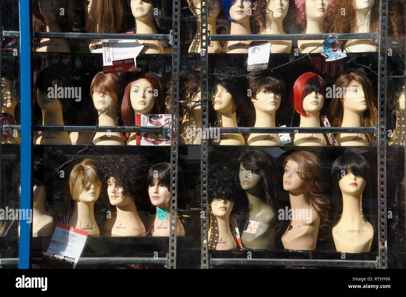Wigs and hairpieces on mannequin heads on metal display shelves in shop  window, East Street, Walworth, South London, UK Stock Photo - Alamy