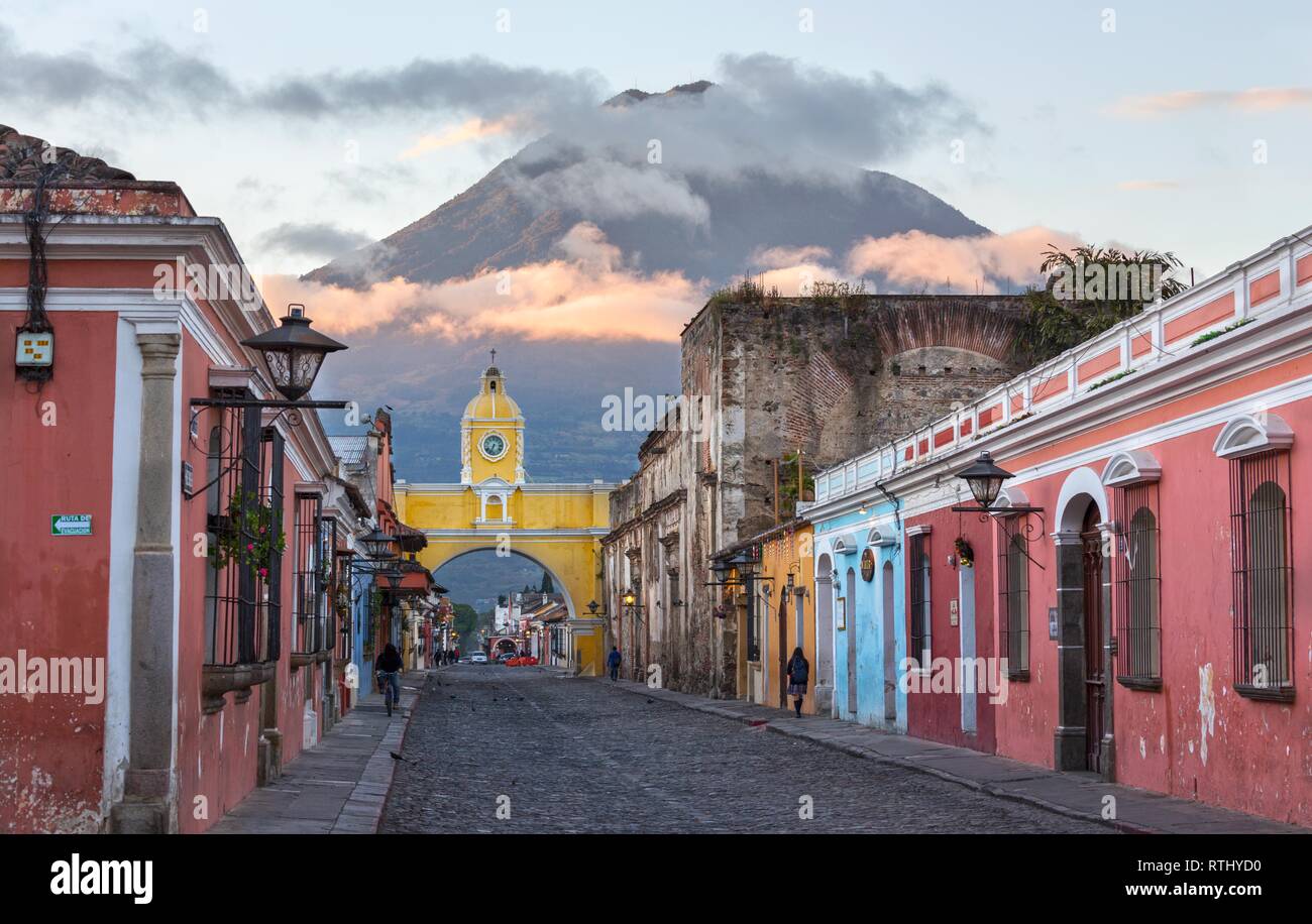 Colonial Architecture and Street Scene during Early Morning Sunrise in Antigua Guatemala with Santa Catalina Arch and Agua Volcano in the Background Stock Photo