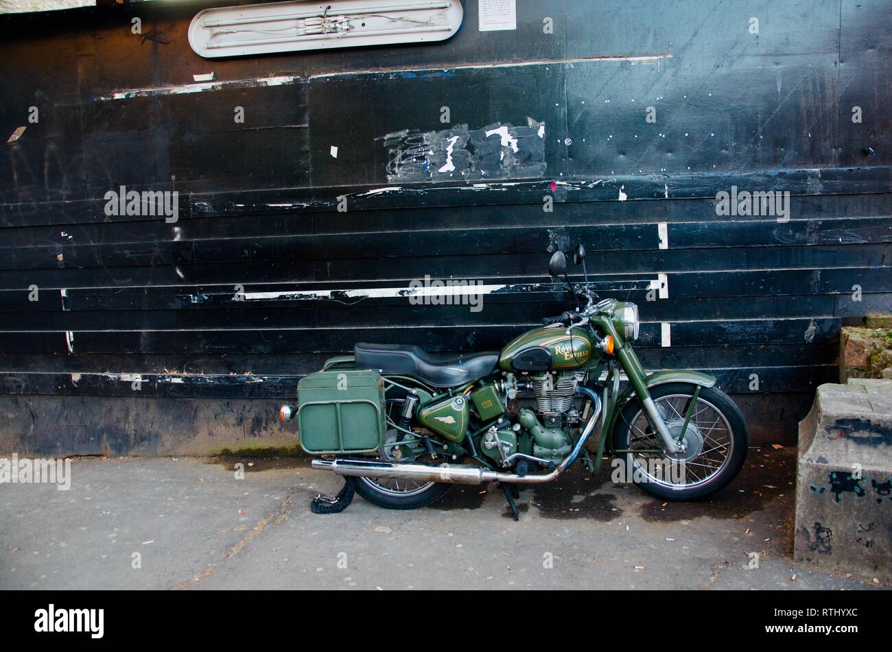 Royal Enfield Bullet 500 military motorcycle parked against dark metal wall, London, UK Stock Photo
