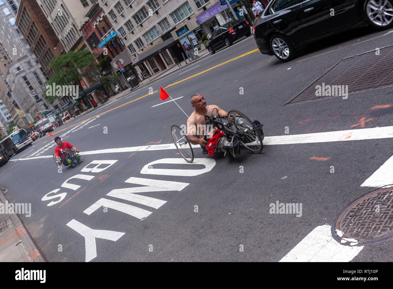 Two men with a tadpole recumbent tricycle along a only bus lane in  E 57th St, Manhattan, New York, USA Stock Photo