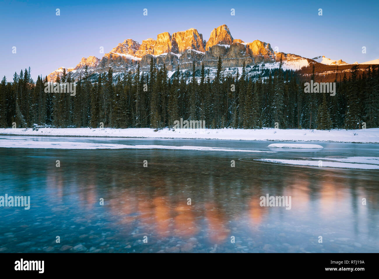 Sunset long exposure of the late sun catching the top of the snow covered Castle Mountain and the Bow River in Banff National Park, Canada Stock Photo