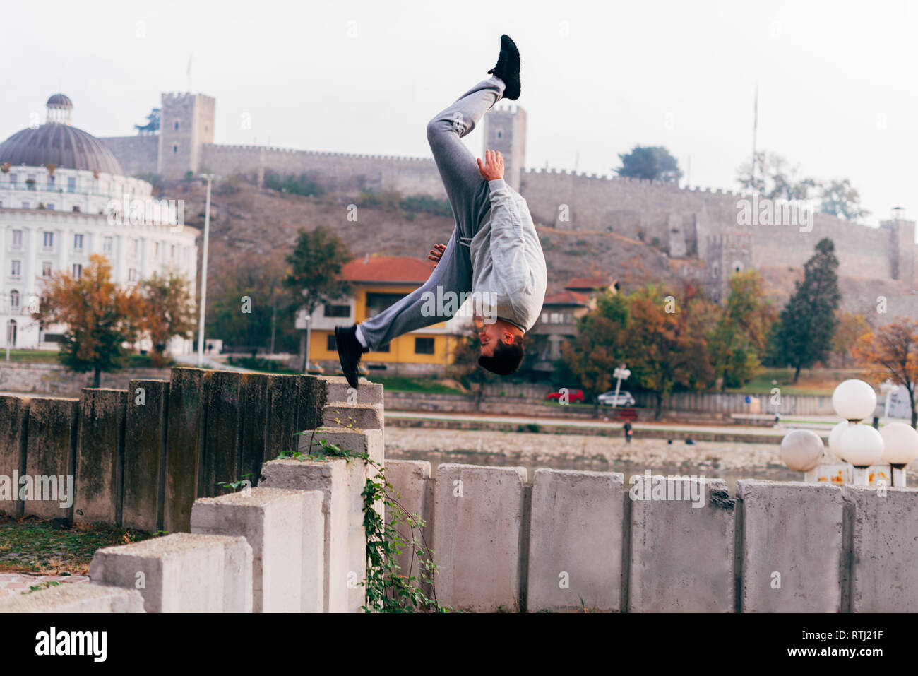 Free runner training parkour jumping on a fence while doing a back flip in the air. Stock Photo