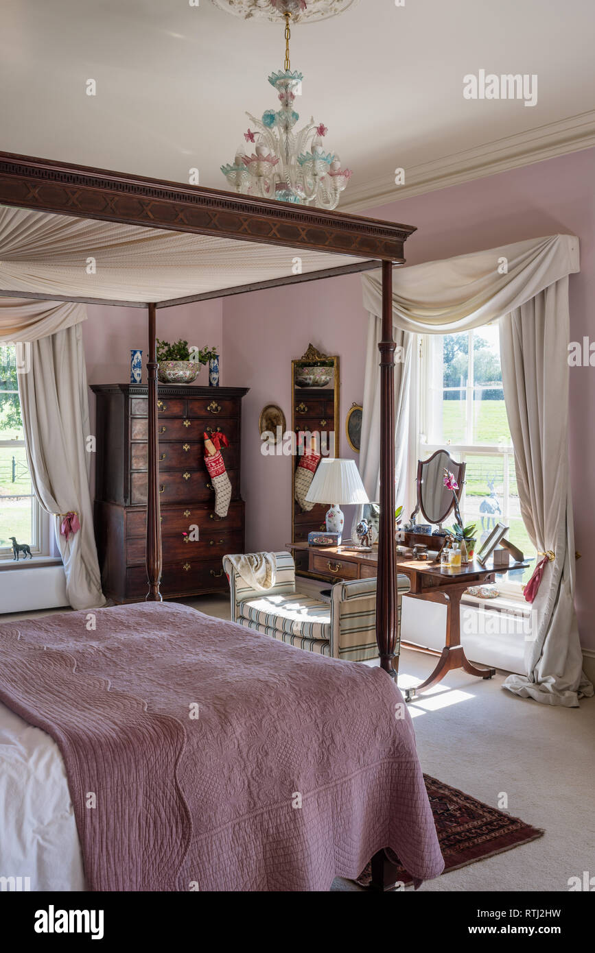 Four-poster bed bought at auction with dressing table at sunlit window Stock Photo