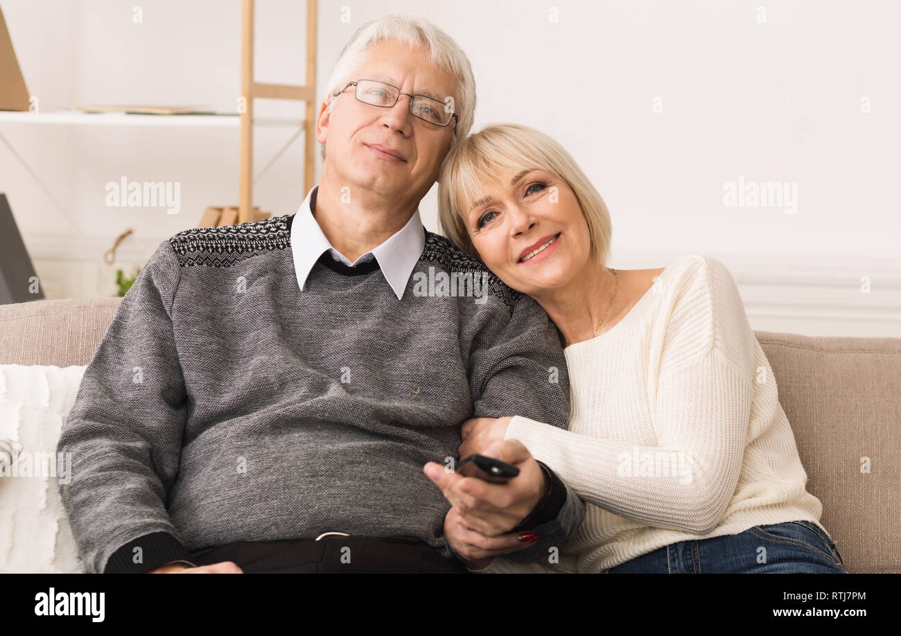 Loving senior couple watching tv with remote control Stock Photo
