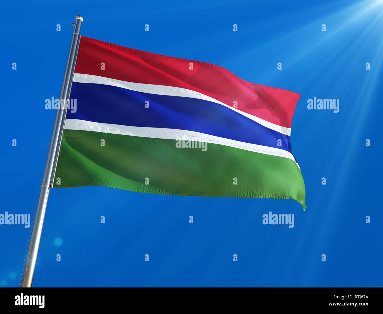 Gambia National Flag Waving on pole against deep blue sky background ...