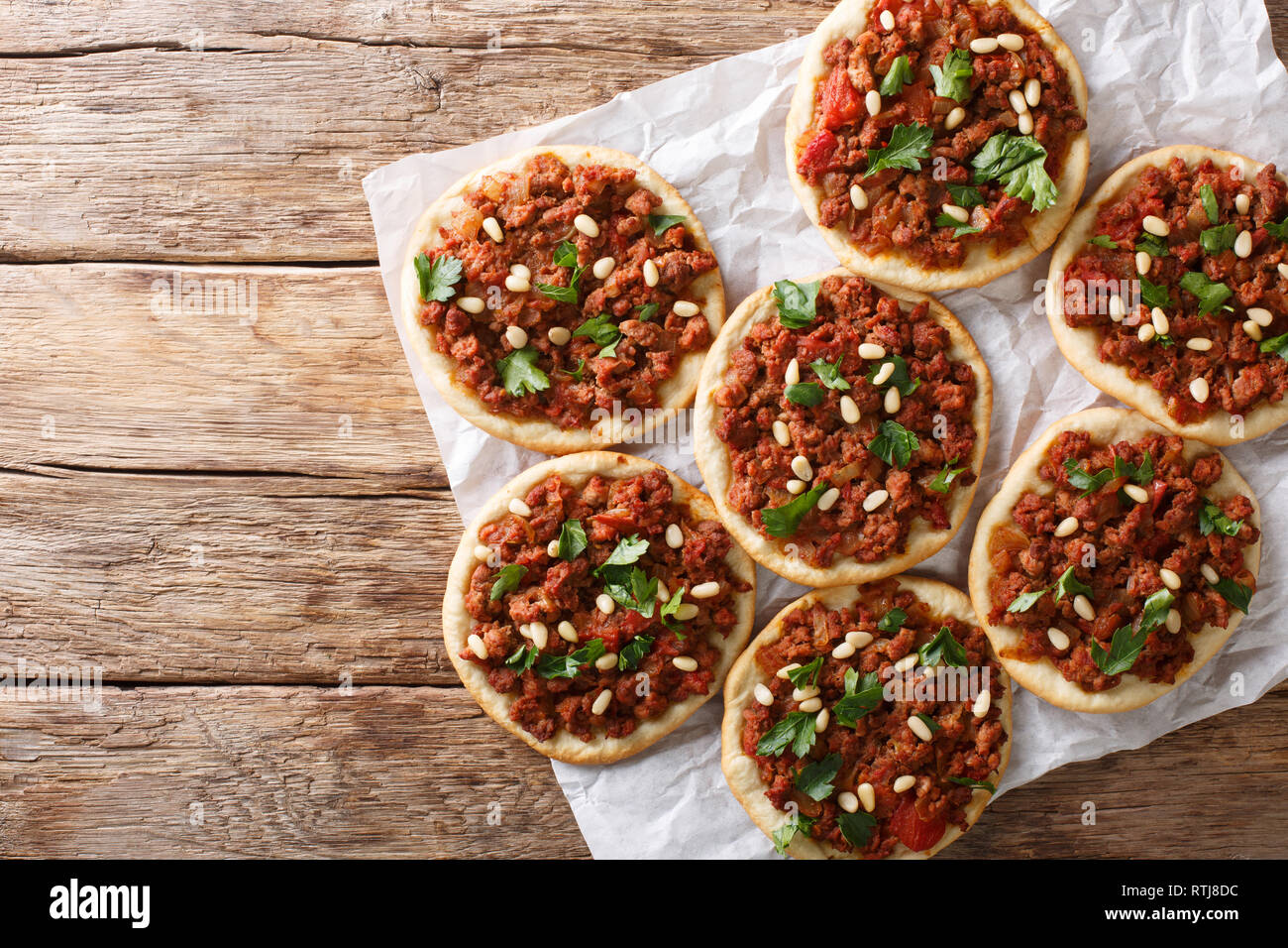 Lebanese Arab pizza with meat, tomatoes, spices and pine nuts closeup on the table. Horizontal top view from above Stock Photo