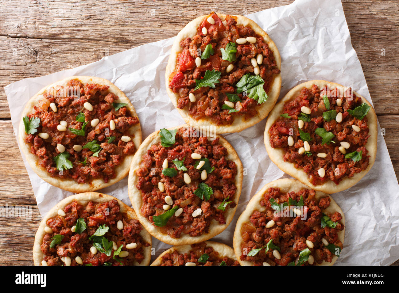 Arab mini pizza with minced meat, tomatoes, onions, spices and pine nuts closeup on the table. horizontal top view from above Stock Photo
