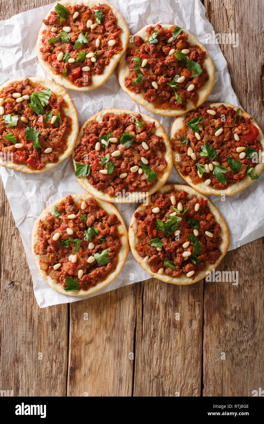 Lebanese Arab pizza with meat, tomatoes, spices and pine nuts closeup on the table. Vertical top view from above Stock Photo