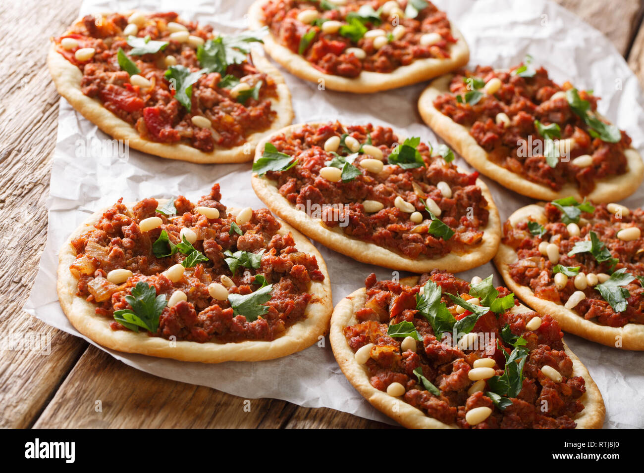 Arab mini pizza with minced meat, tomatoes, onions, spices and pine nuts closeup on the table. horizontal Stock Photo