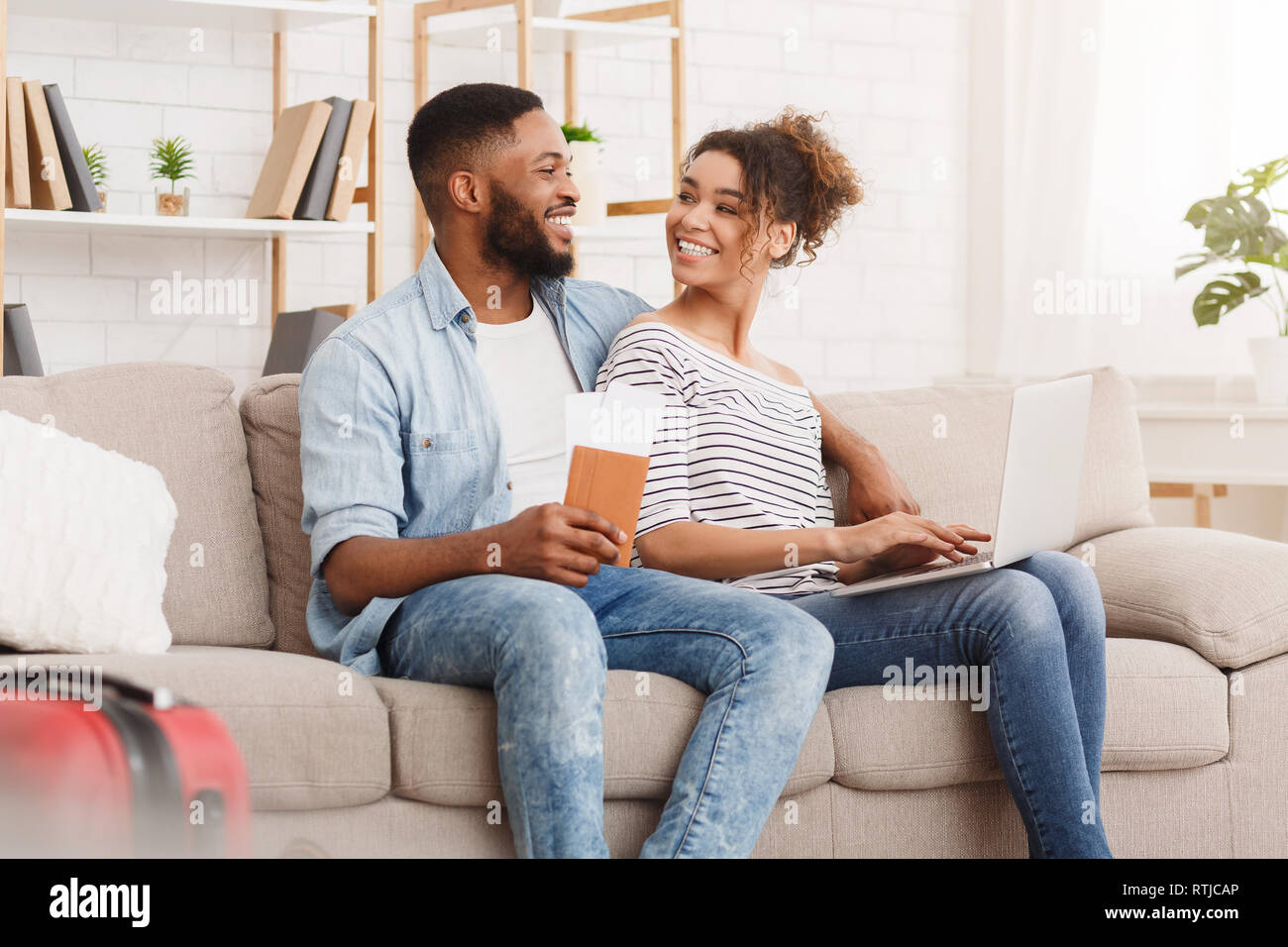 Planning tour. African-american couple using laptop at home Stock Photo ...