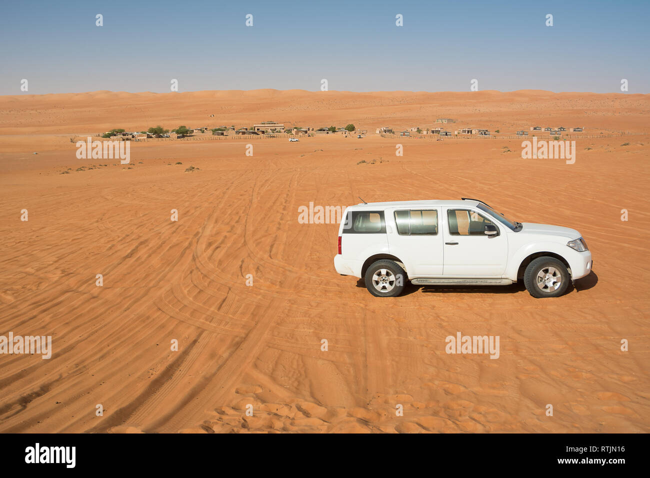 Off-road vehicle in the Wahiba Sand Desert and Bedouin camp in the background (Oman) Stock Photo