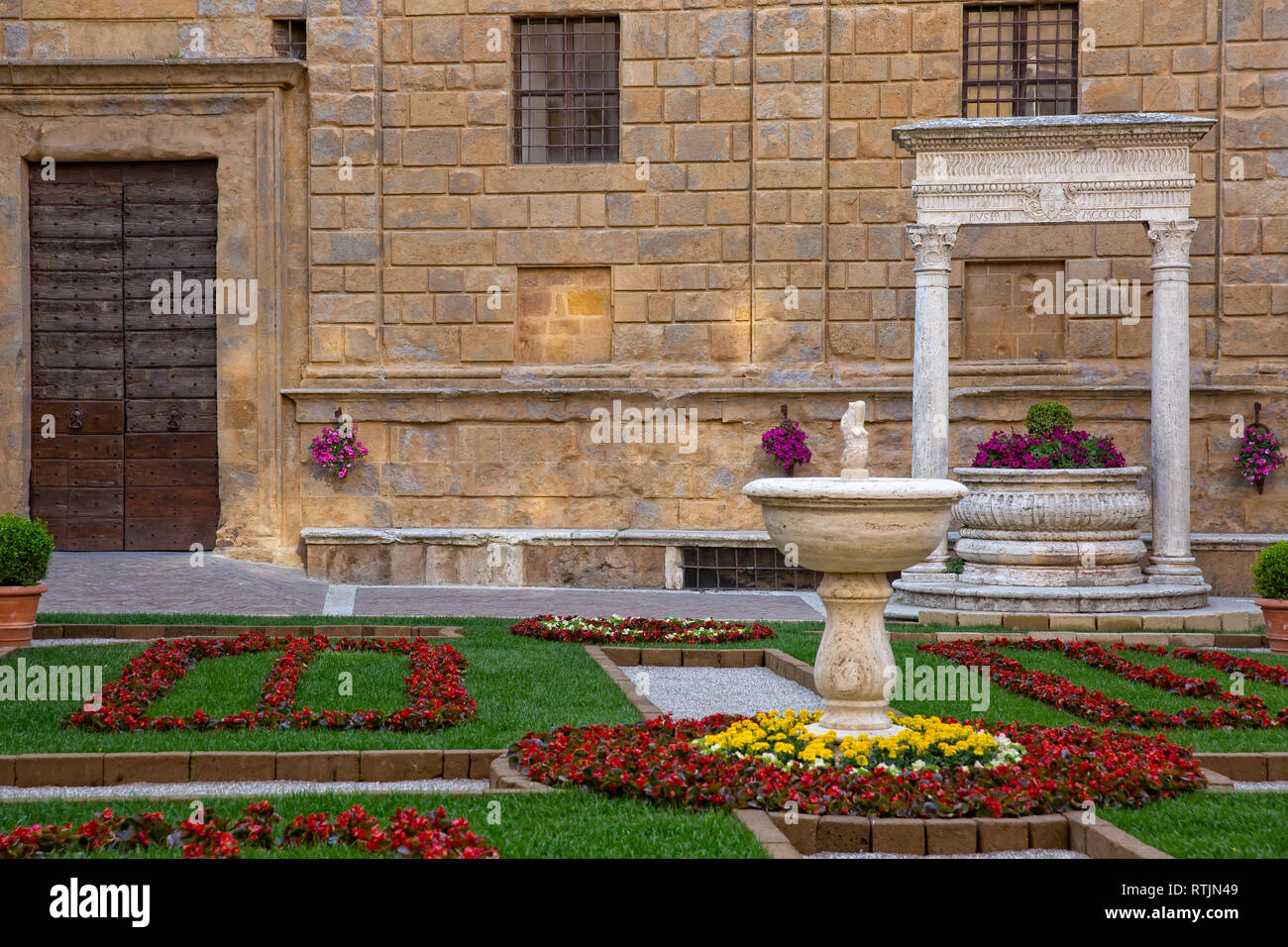 Old well in the main square of Pienza. The travertine well of the Rossellino and the front of Palazzo Piccolomini in Pienza, Tuscany, Italy Stock Photo