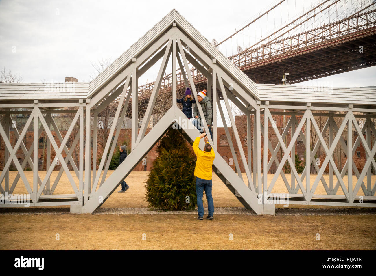 Siah Armajani's experiential public art sculpture, 'Bridge Over Tree' is enjoyed by visitors to Brooklyn Bridge Park, between the Manhattan and Brooklyn bridges, in New York on Saturday, February 23, 2019. The 91-foot long piece with stairs in the center lifts the participant over a lone evergreen tree  and it is the first time the 1970 piece has been displayed in almost 50 years. The Met Breuer is hosting a retrospective of the Minneapolis based artists' works and 'Bridge Over Tree' will be on display in the park until September 29. (Â© Richard B. Levine) Stock Photo