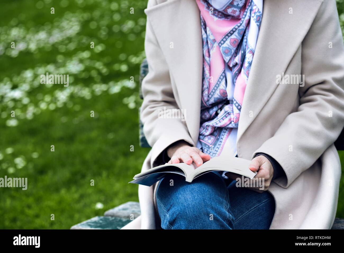 the girl is sitting on a park bench and reading a book Stock Photo - Alamy