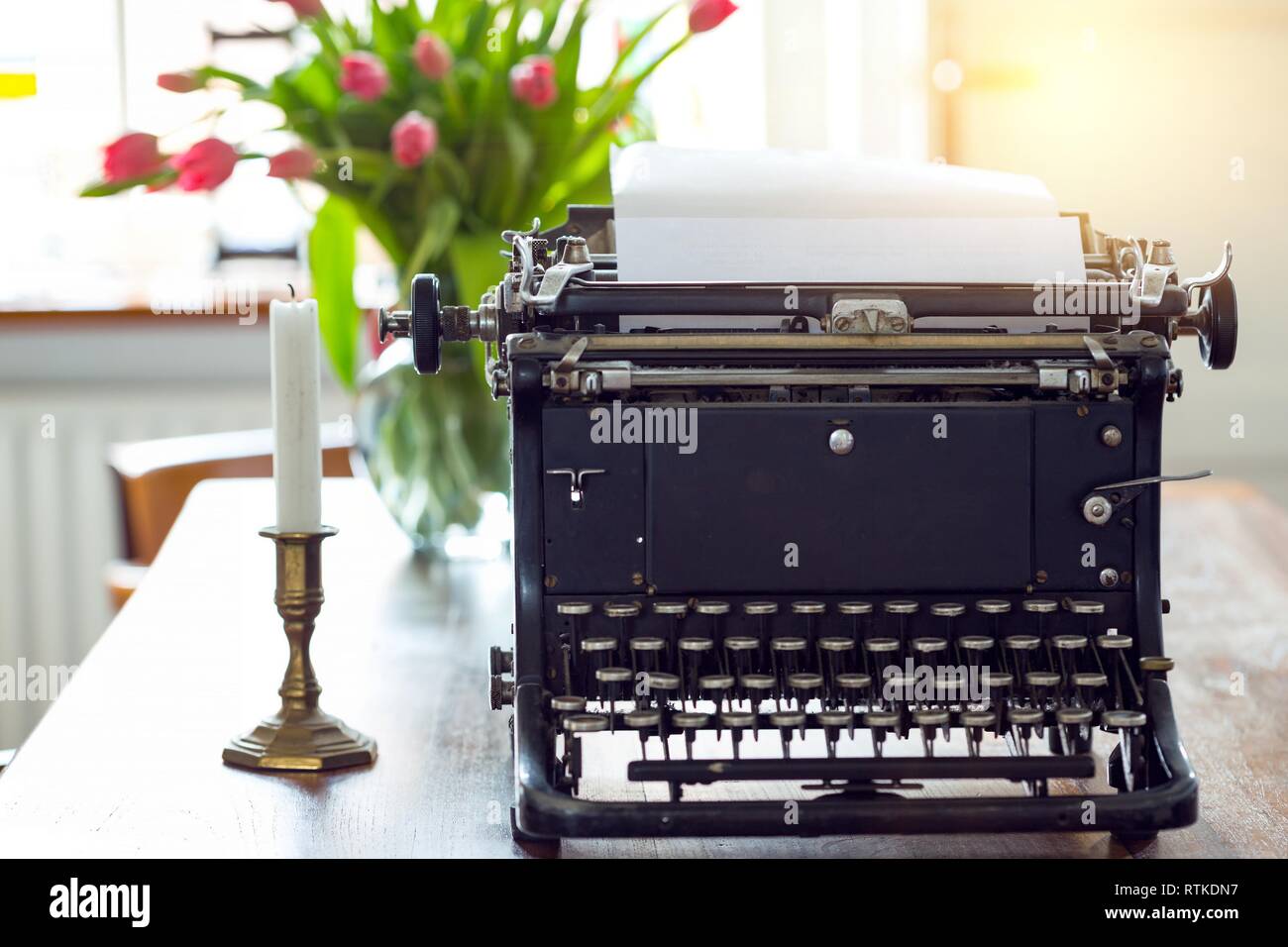the old typewriter standing on the table near the window Stock Photo