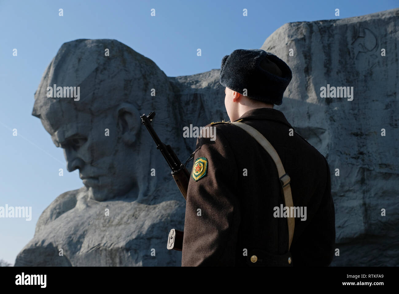 A Belarusian Guard of Honor stands firm next to the gigantic sculptural image of a Soviet combatant in front of a banner commonly known as 'Courage' at the war memorial complex 'Brest Hero Fortress' located in Brest fortress formerly known as Brest-Litovsk Fortress, a 19th-century Russian fortress in the city of Brest, Belarus Stock Photo