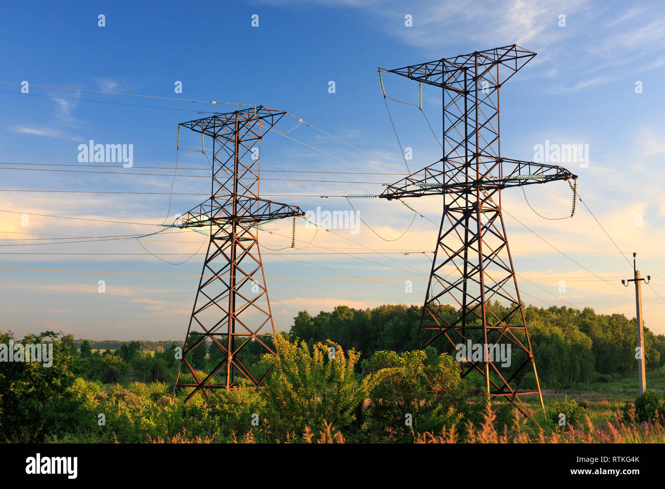 High-voltage power transmission towers in sunset sky background Stock ...