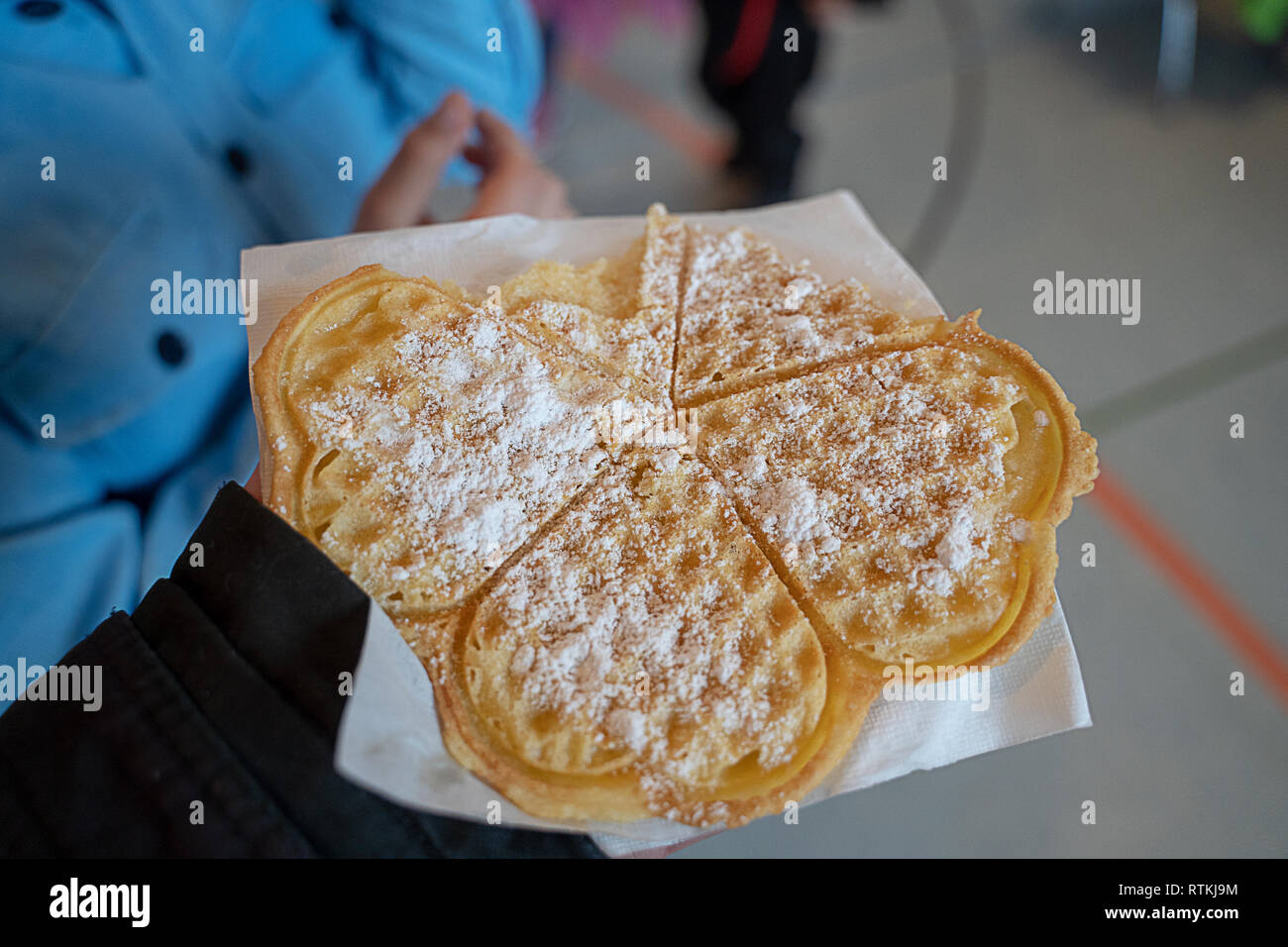 A german typical waffle in a hand with powdered sugar. Partially eaten