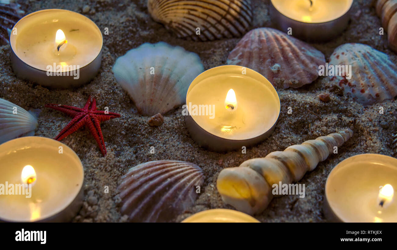 Six candles and some seashells on the sand. The decoration is nice to