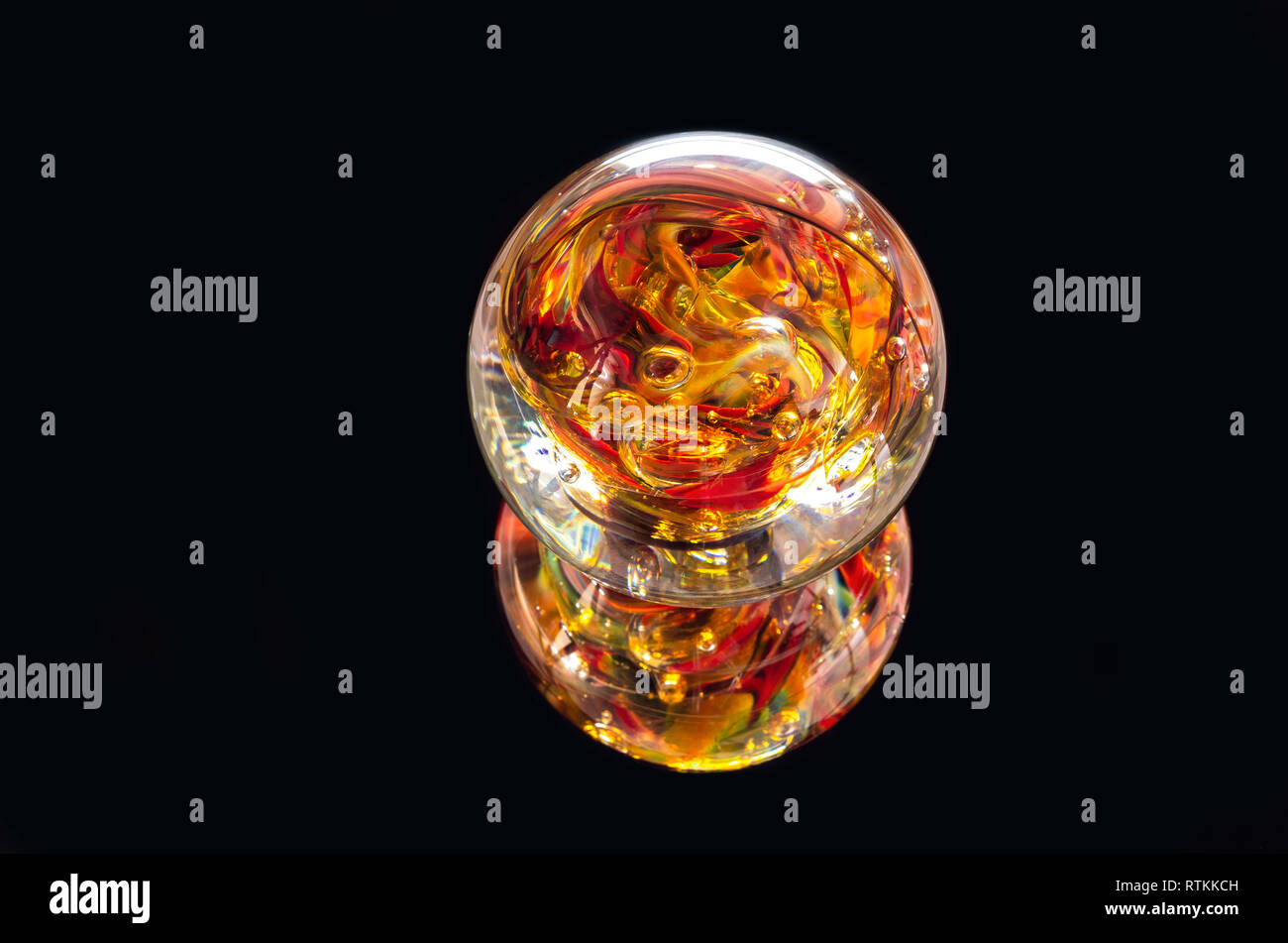 vibrant colored glass sphere and reflection isolated against black Stock Photo