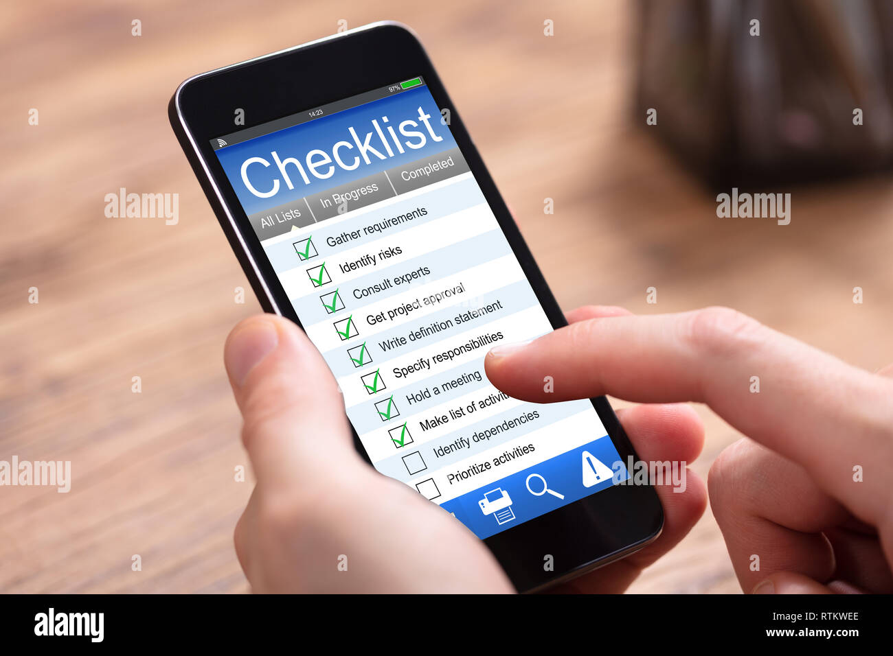 Close-up Of Human Filling Checklist Form On Cellphone At Wooden Desk Stock Photo