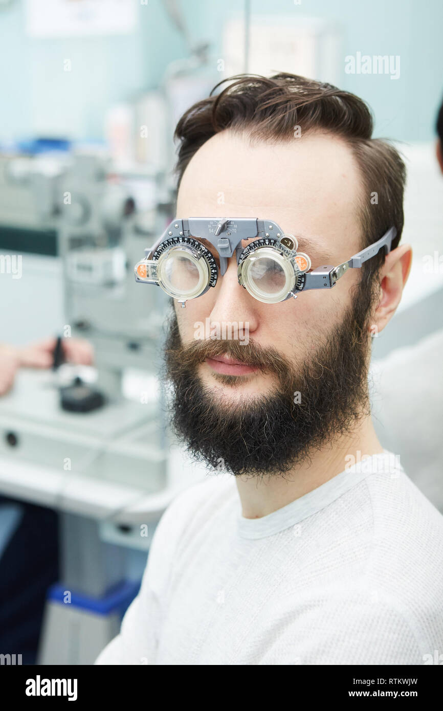 Young man with trial frames in ophthalmologist clinic Stock Photo