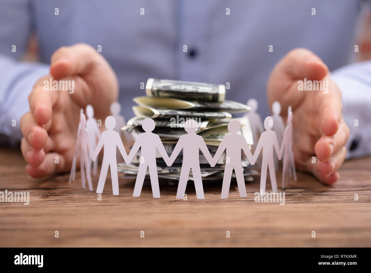 Person's Hand Protecting Stacked Banknotes Surrounded By Human Figures ...
