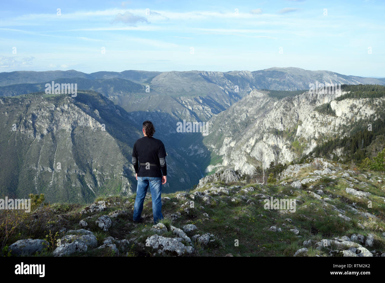 Young man stands in the edge of Tara Canyon and Tara River - Durmitor National Park. Near Zabljak, Montenegro. Stock Photo