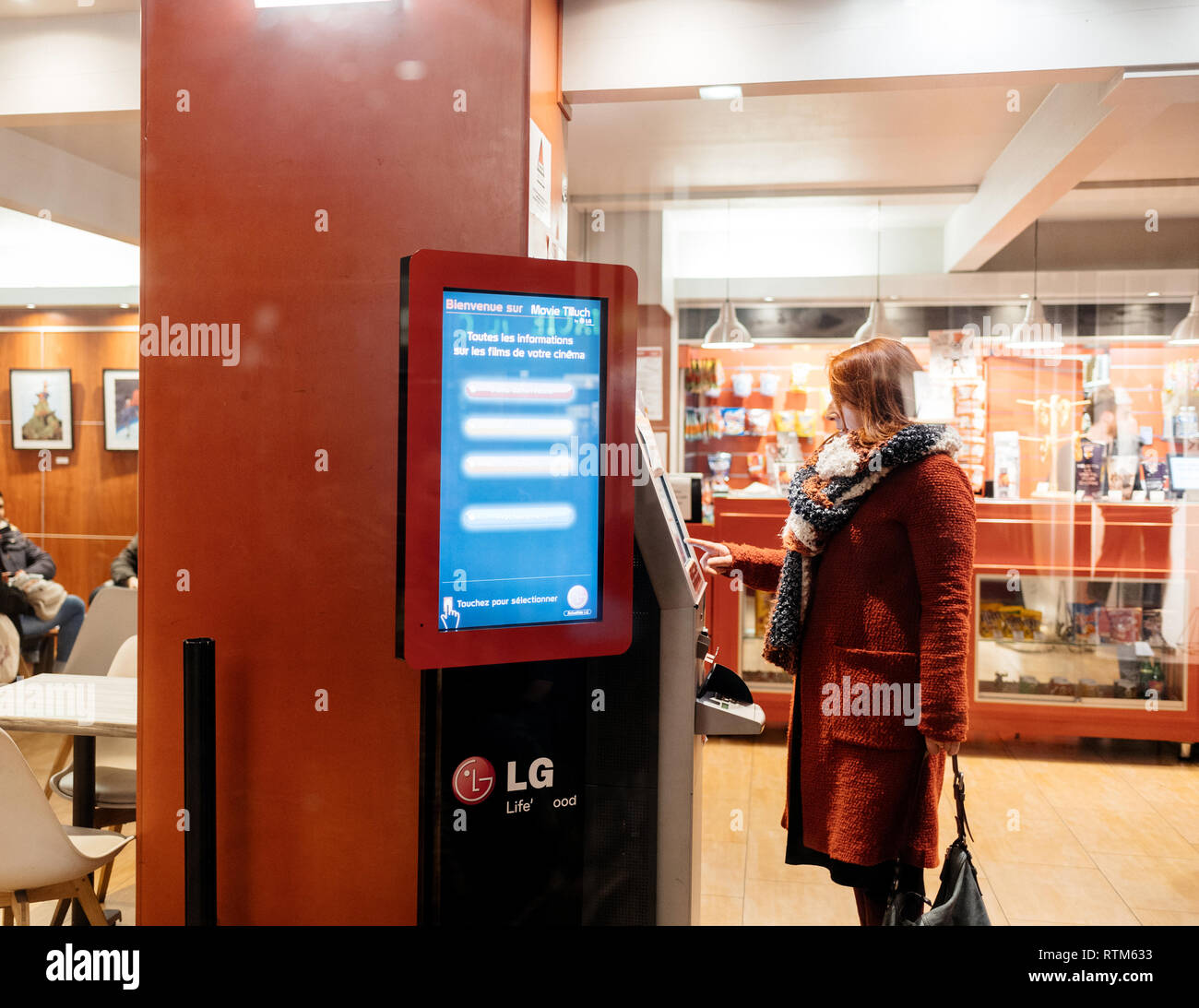 STRASBOURG, FRANCE - NOV 21, 2017: View from the street of single woman buying ticket from vending machine inside Cinema building  Stock Photo