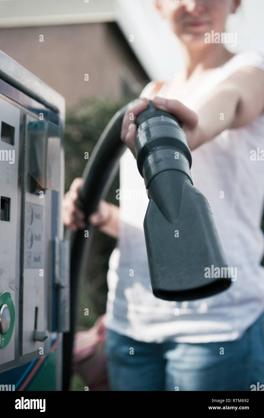 Woman holding showing vacuum cleaner hose at modern self car wash station Stock Photo
