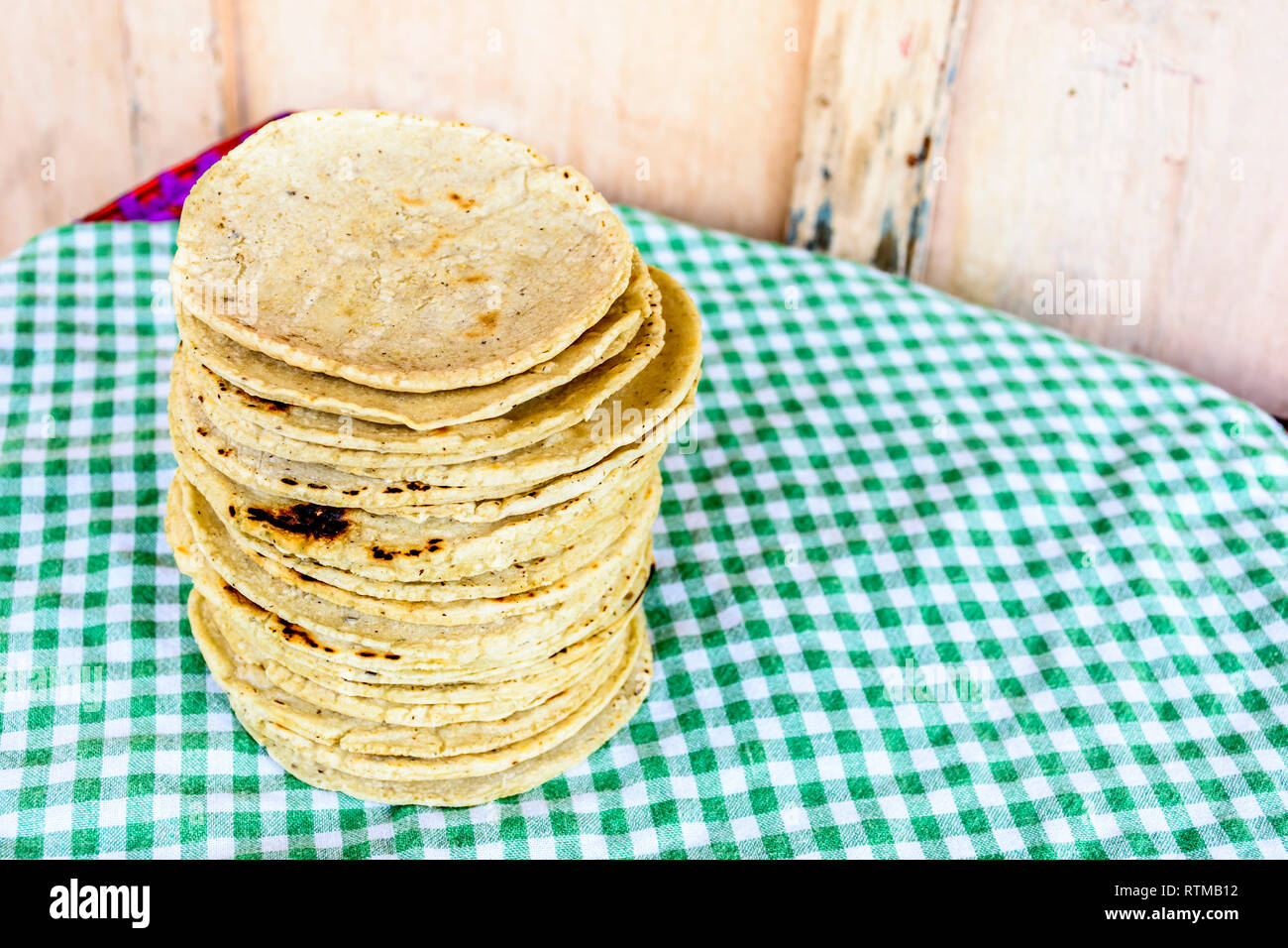 Stack of traditional handmade Guatemalan corn tortillas a staple food in Guatemala on green checkered tablecloth Stock Photo