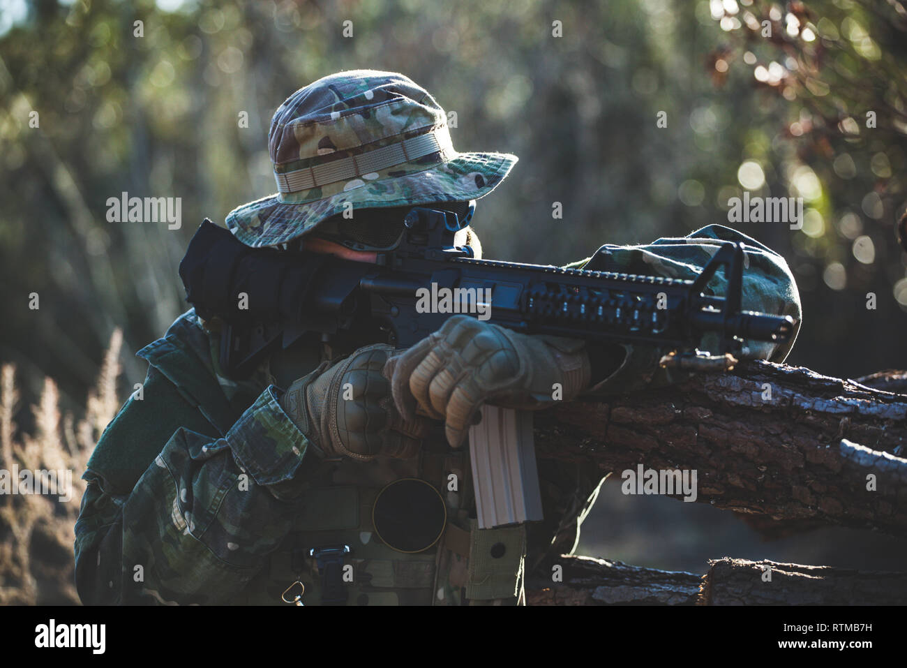 Airsoft military game player in camouflage uniform with armed assault rifle. Stock Photo