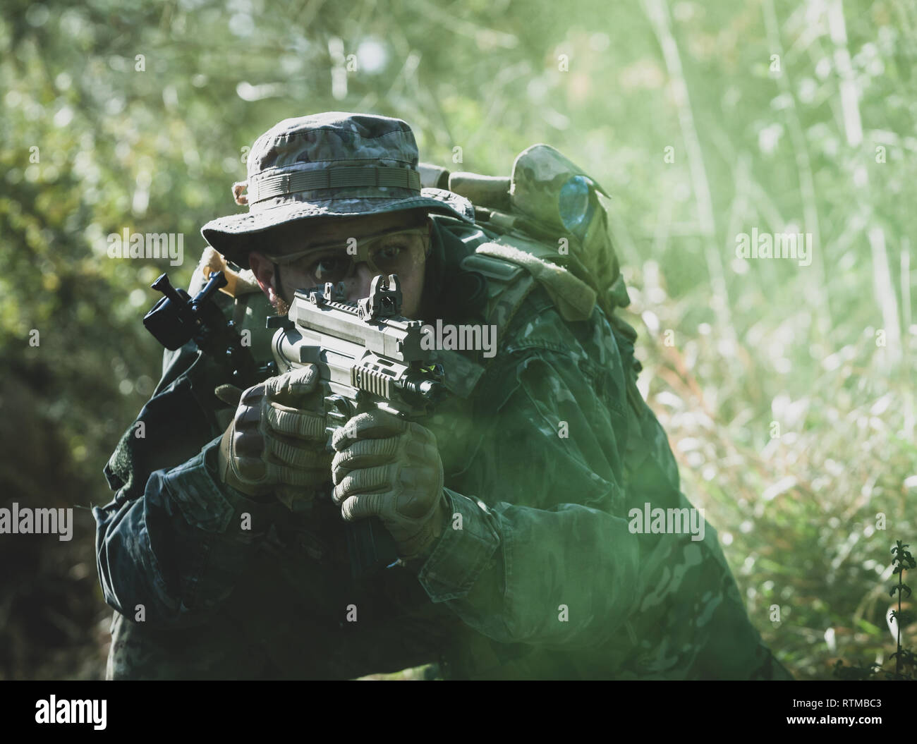 Airsoft military game player in camouflage uniform with armed assault