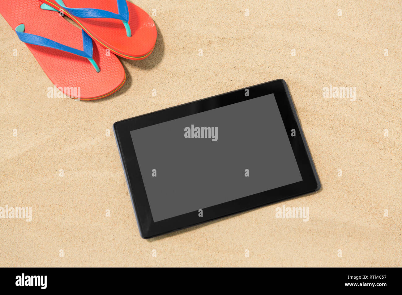 tablet computer and flip flops on beach sand Stock Photo Alamy