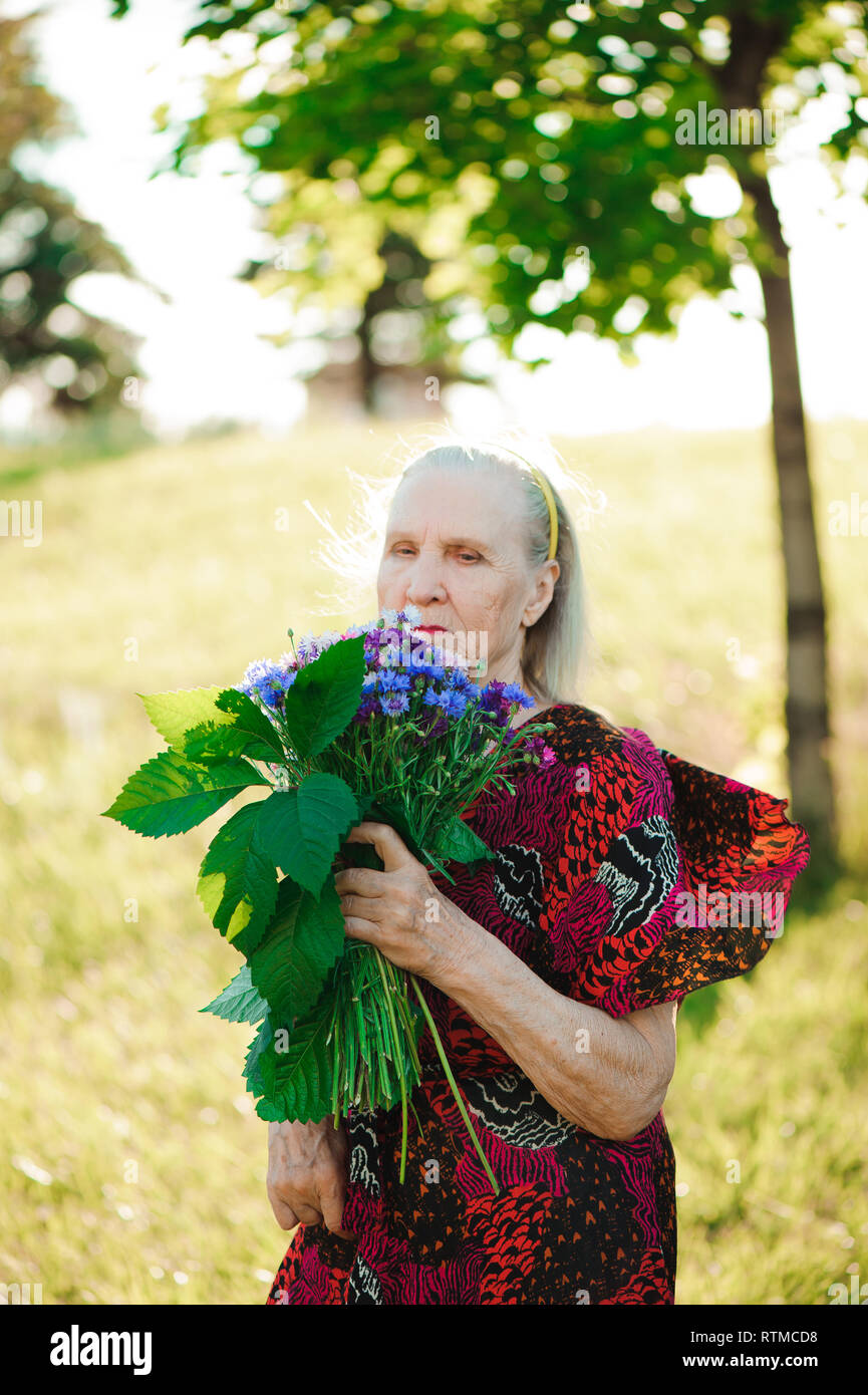 80 year old woman with a bouquet of flowers in her hands. Stock Photo